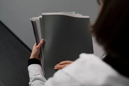 Close-up of a businesswoman holding and reviewing documents in an office setting.