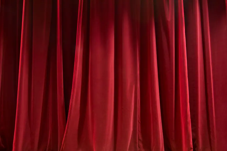 Blinded curtains of red color and made of silk fabric hanging under bright light