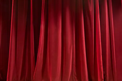 Blinded curtains of red color and made of silk fabric hanging under bright light