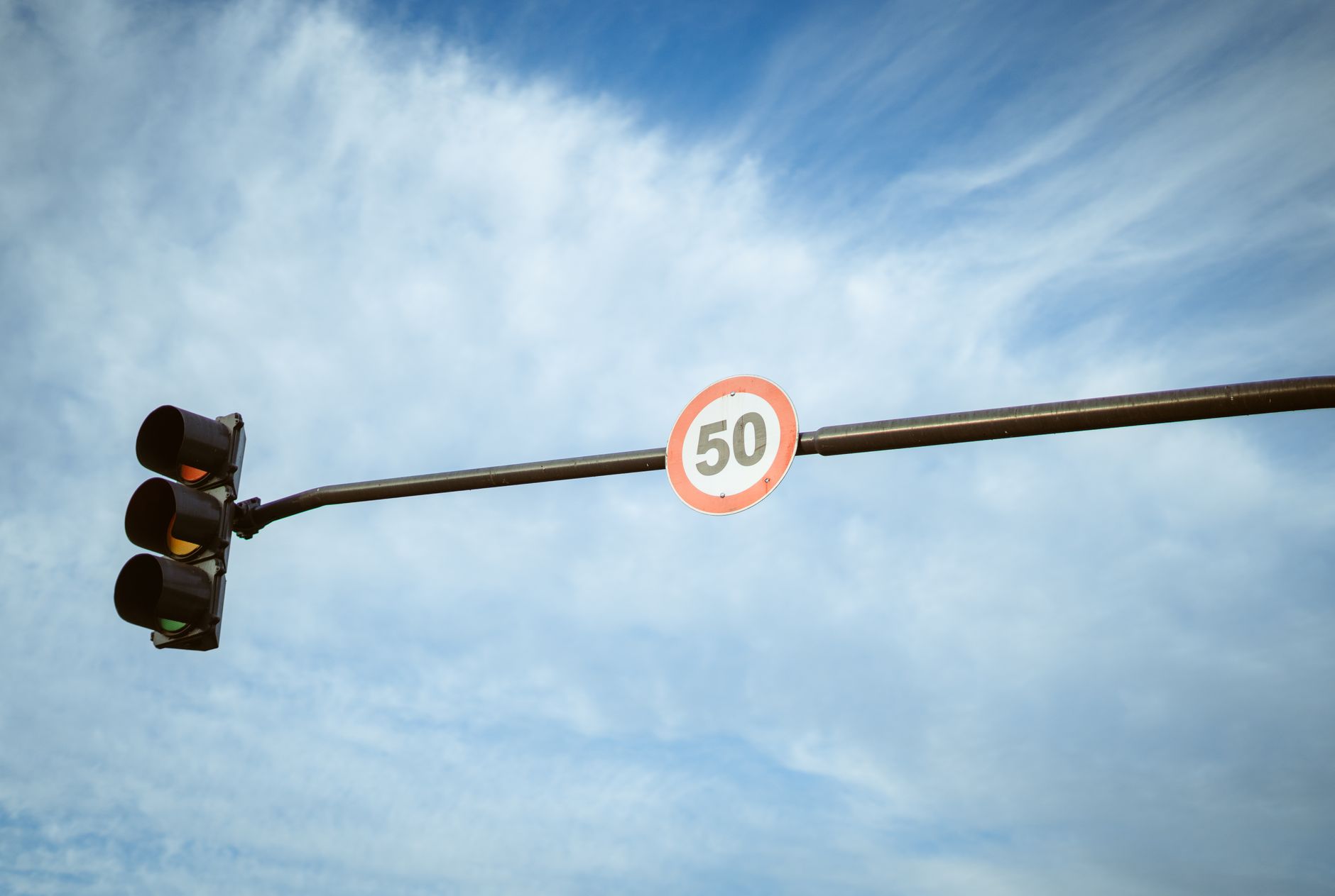 A traffic light and speed limit sign under a blue sky in Buenos Aires, Argentina.