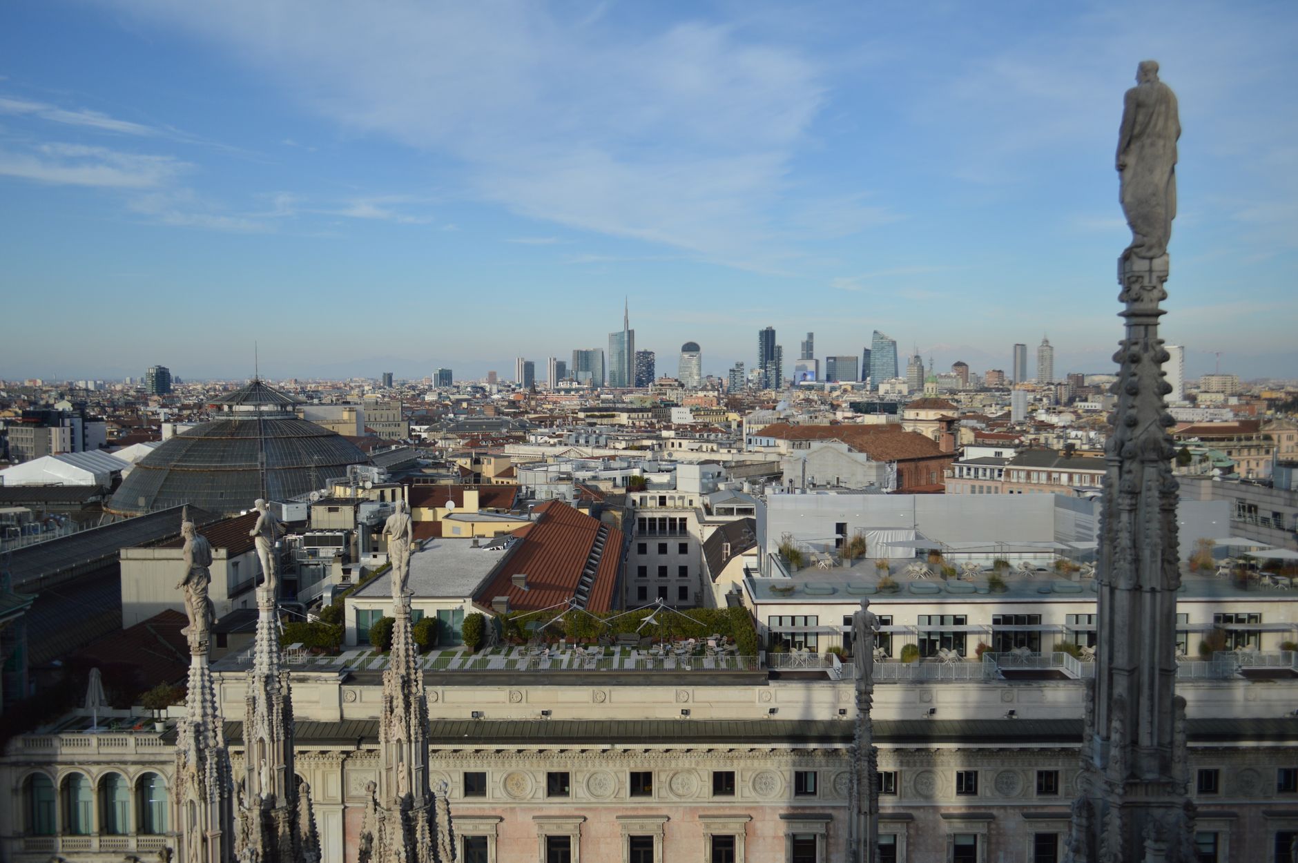 Captivating aerial view of Milan's skyline from atop the Duomo with a clear blue sky backdrop.