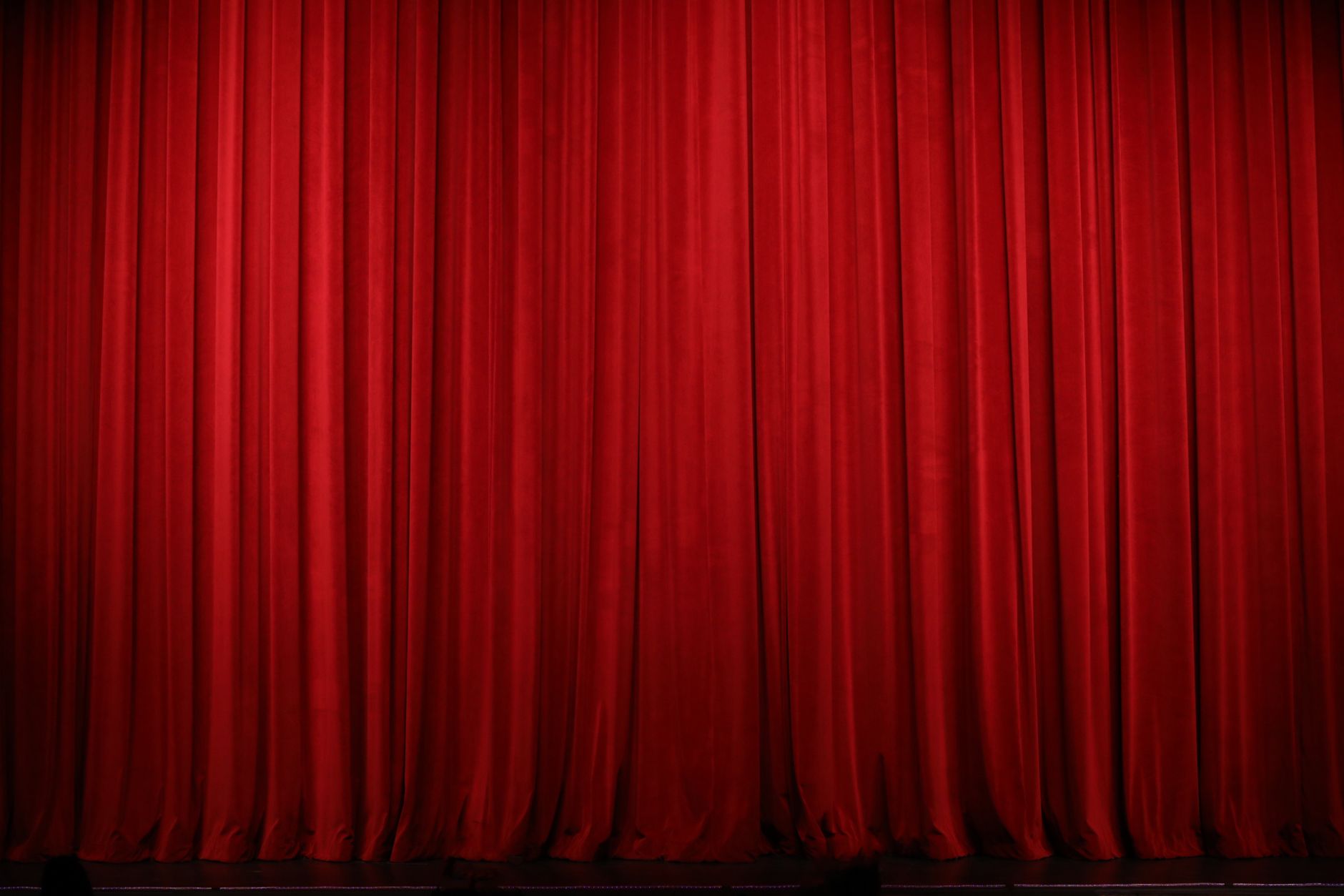 Elegant red theater curtains creating a dramatic stage backdrop indoors.