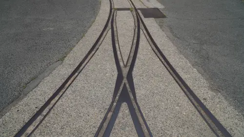 Close-up view of intersecting steel rail tracks embedded in concrete pavement.