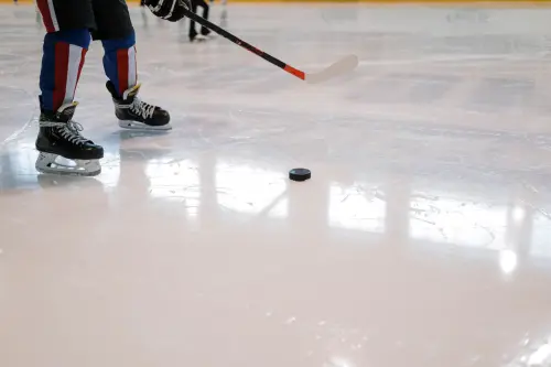 Dynamic shot of a hockey player maneuvering with stick and puck on ice rink.