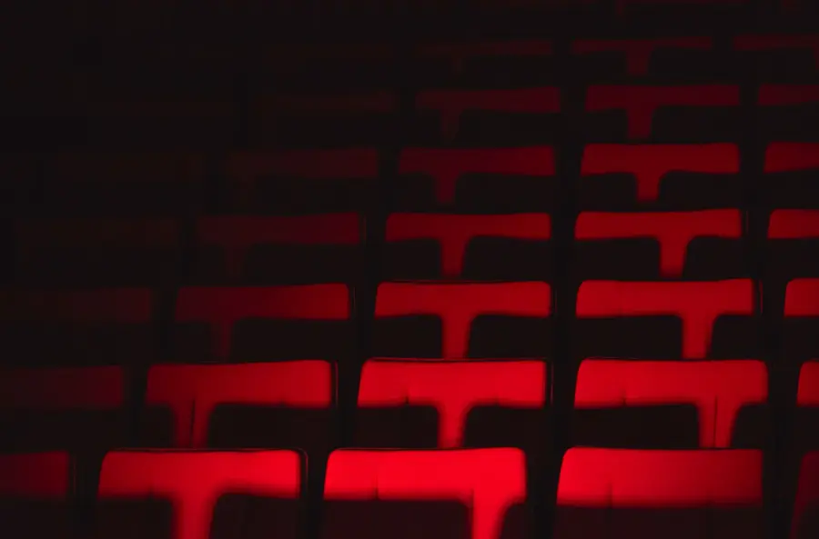 Rows of empty theater seats highlighted by dramatic lighting, creating a moody atmosphere.