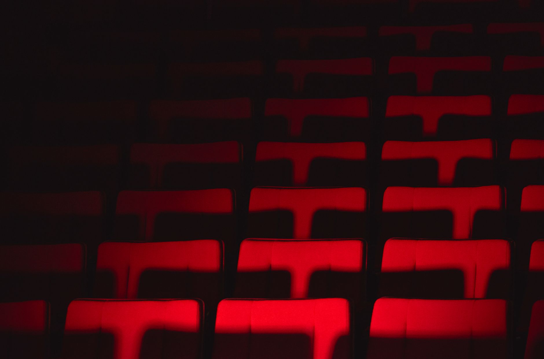 Rows of empty theater seats highlighted by dramatic lighting, creating a moody atmosphere.