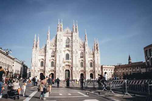 Capture of the majestic Milan Cathedral, showcasing its stunning Gothic architecture in a lively city square.