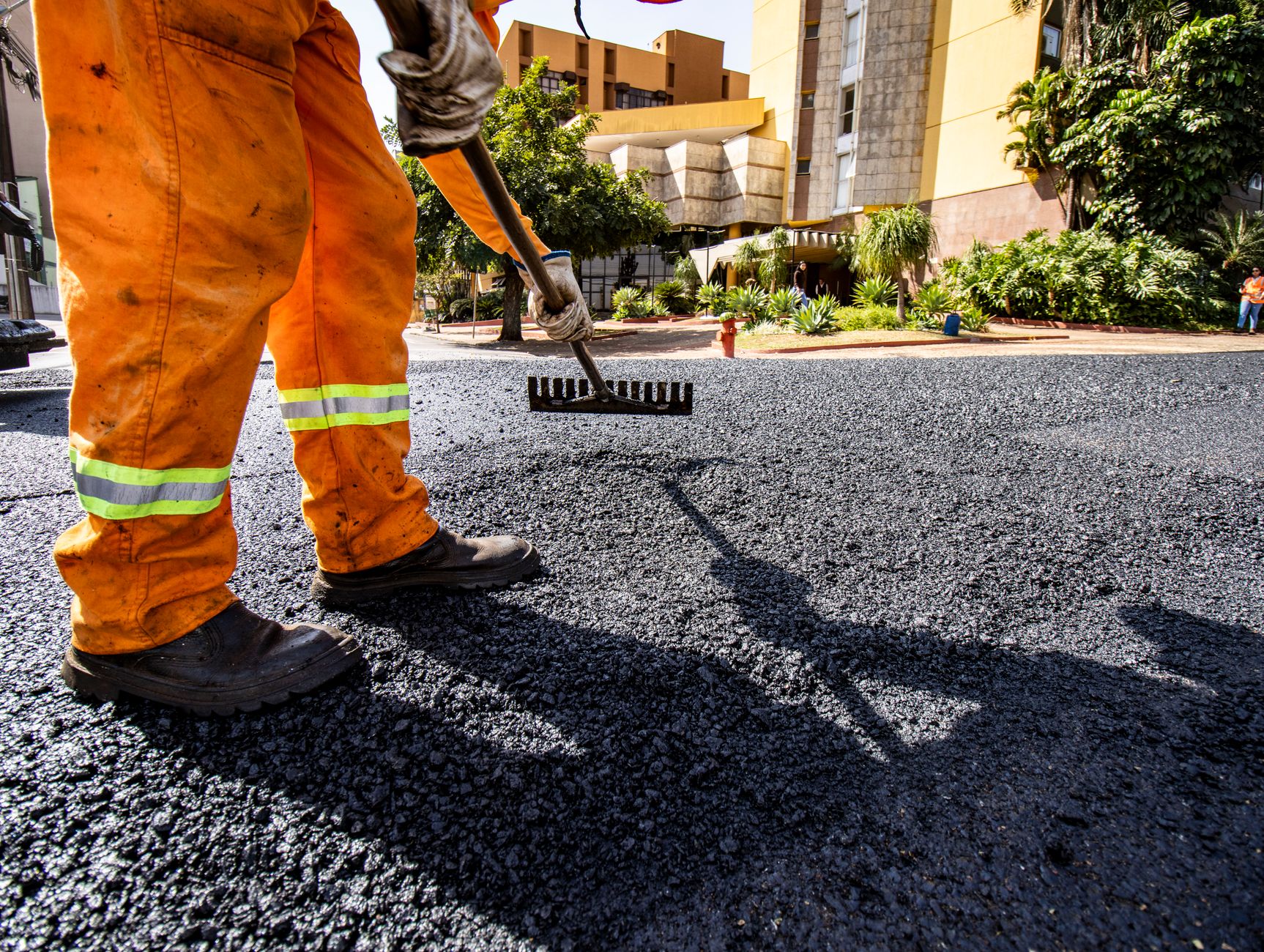 Worker in orange gear paving a road in Londrina city during daytime.