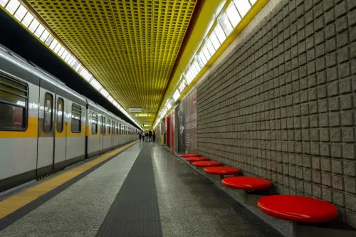 Empty subway platform with yellow ceiling and red benches, modern design.