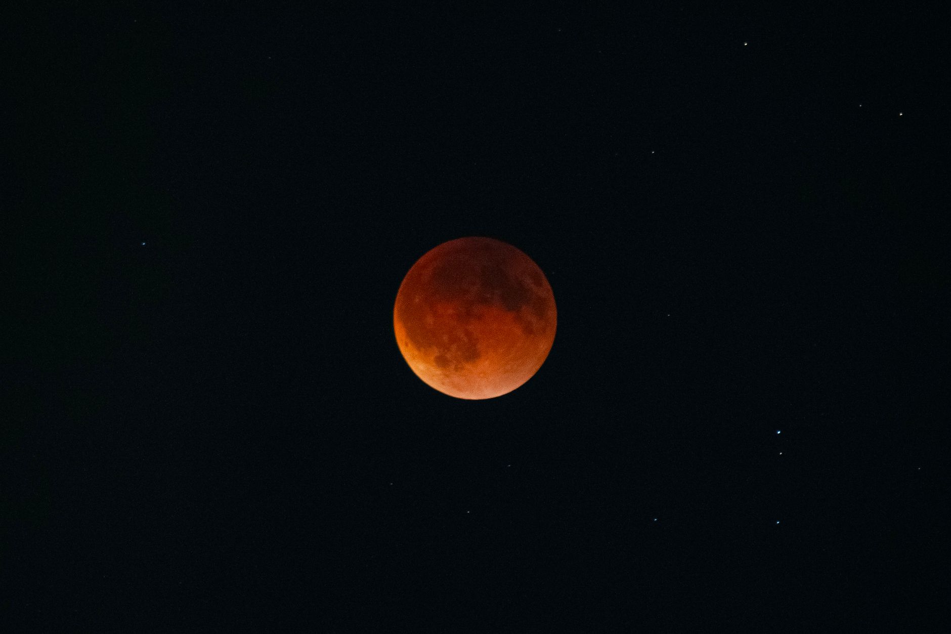 Capture of a blood moon during a lunar eclipse surrounded by stars in the night sky.
