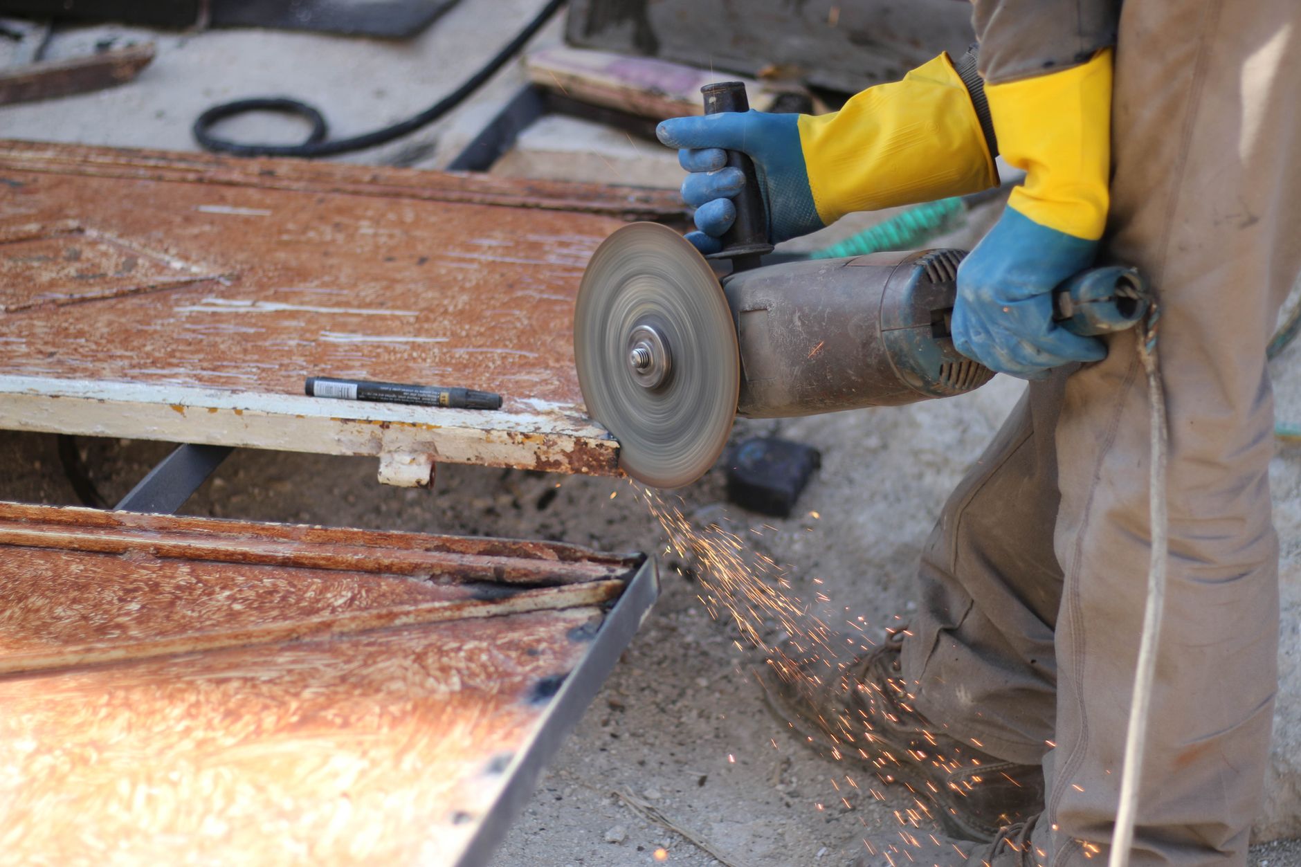Worker using an electric saw to cut metal, generating sparks, showcasing industrial work in Idlib, Syria.