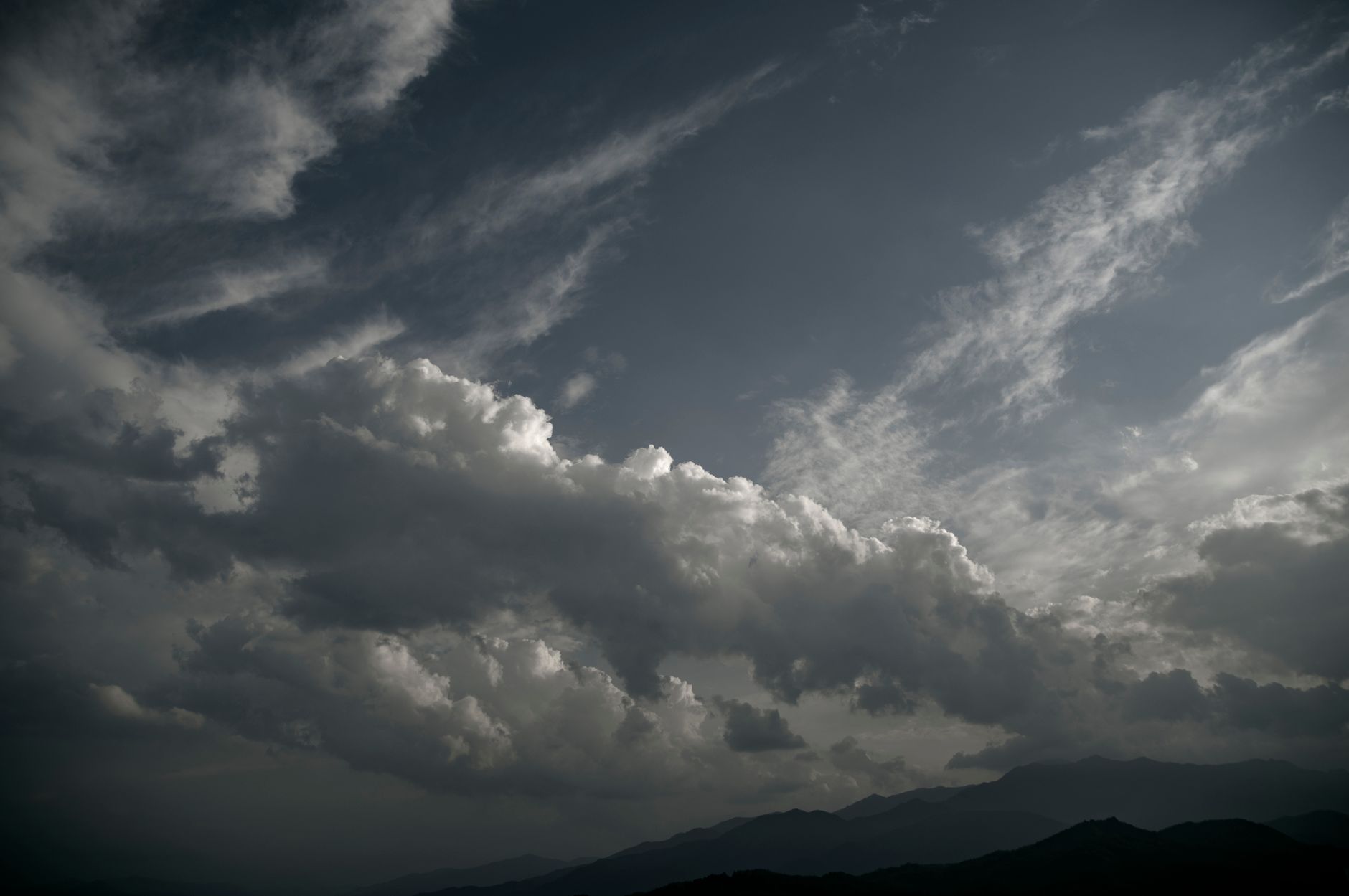 Moody cloudscape with dramatic overcast clouds over distant mountains.