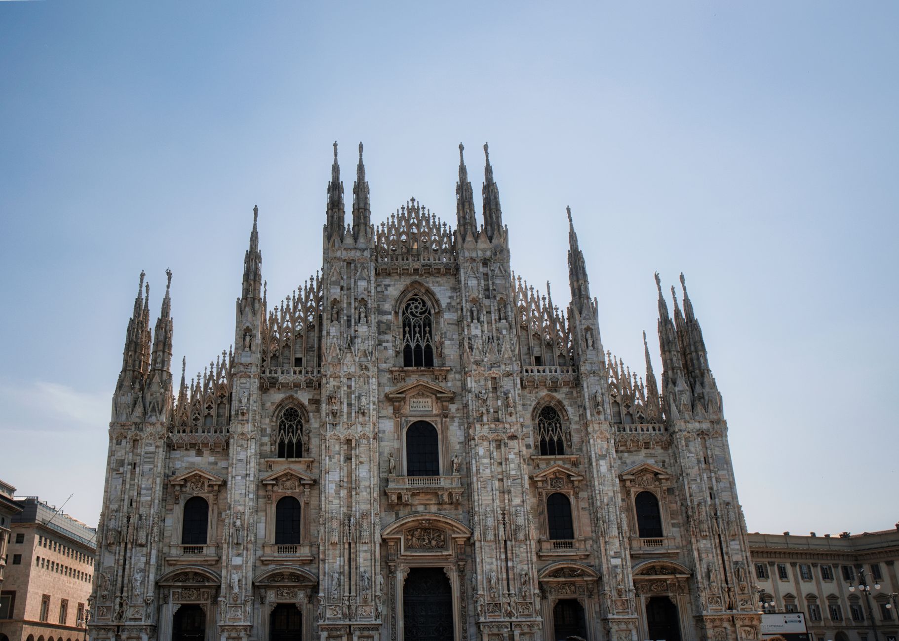 Capture of Milan Cathedral's intricate gothic facade under a clear blue sky in Milan, Italy.