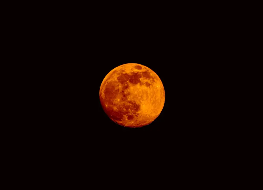 Stunning vibrant orange blood moon against a dark night sky, showcasing lunar texture.