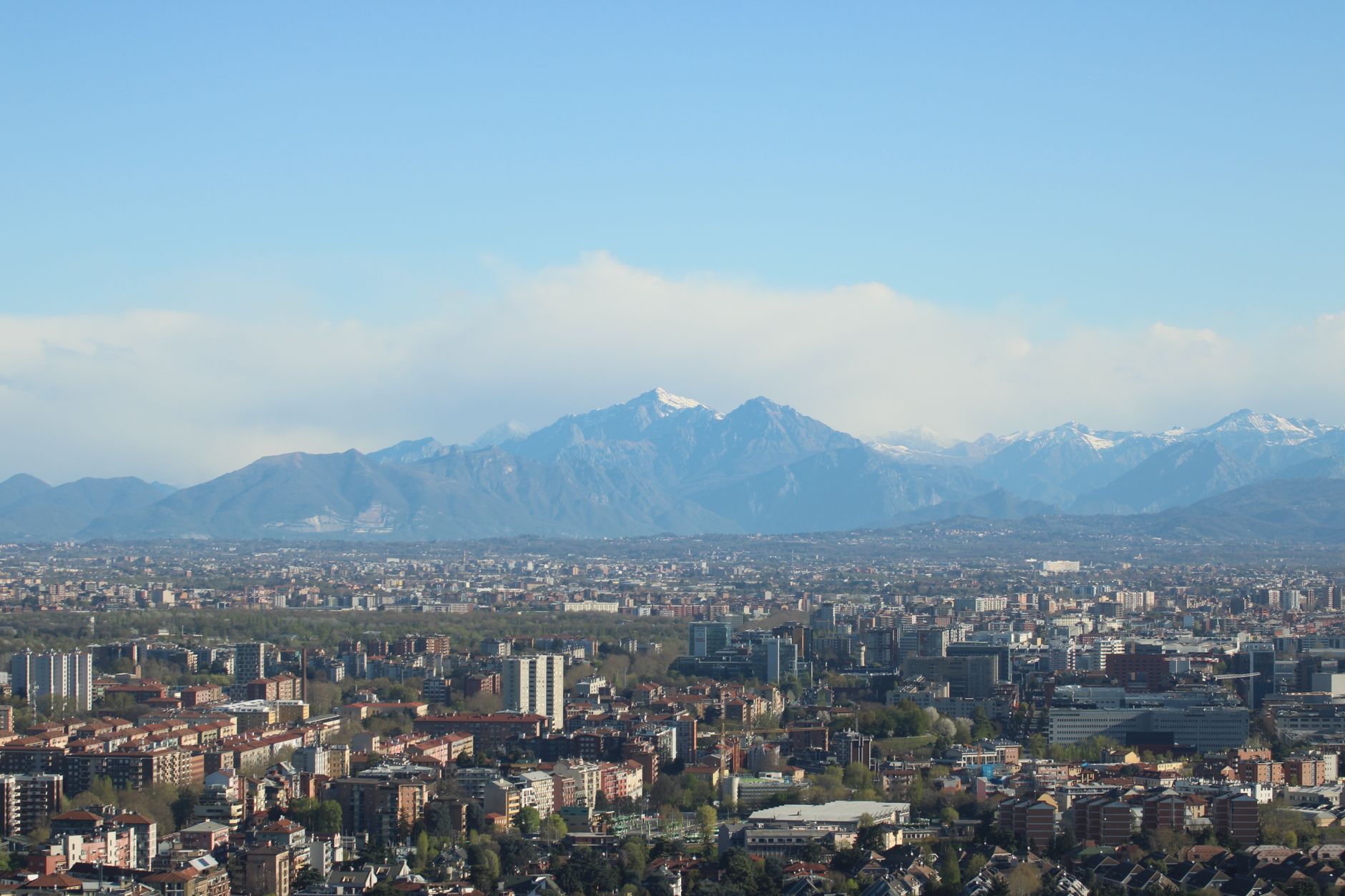 Stunning aerial view of Milano cityscape with the Alps in the background, showcasing urban and natural landscapes.