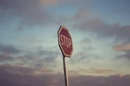 Moody stop sign silhouette against a scenic sunset sky with clouds.