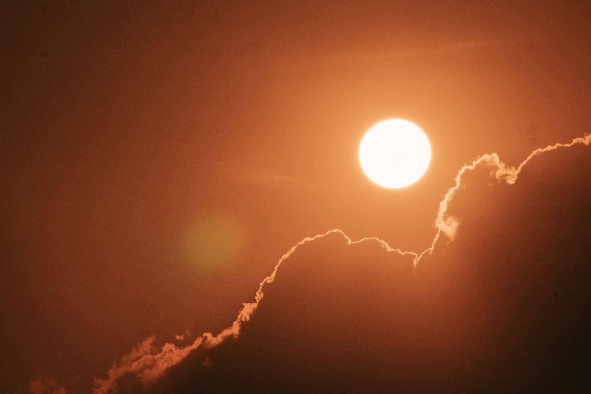 Captivating sun setting behind clouds, creating a warm and dramatic sky scene.